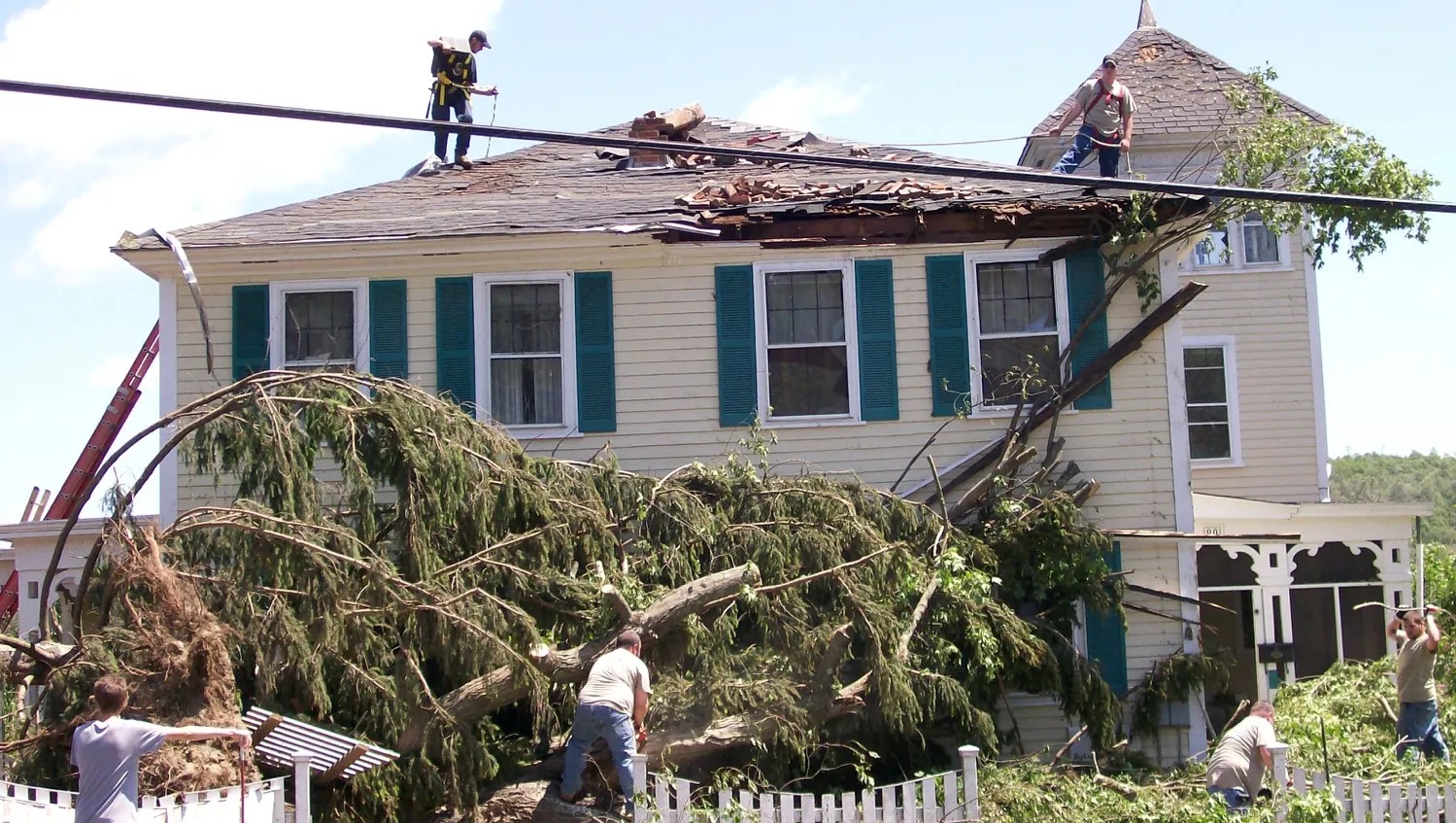 Caitria's home in Monson right after the June 2011 tornado: the roof torn open, a tree down across the front, neighbours already at work.